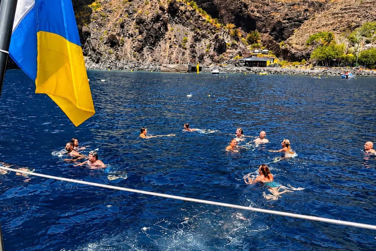 Guests swimming beside the Tenerife coast during a private Freebird catamaran charter, with time for swimming during the exclusive group boat trip.