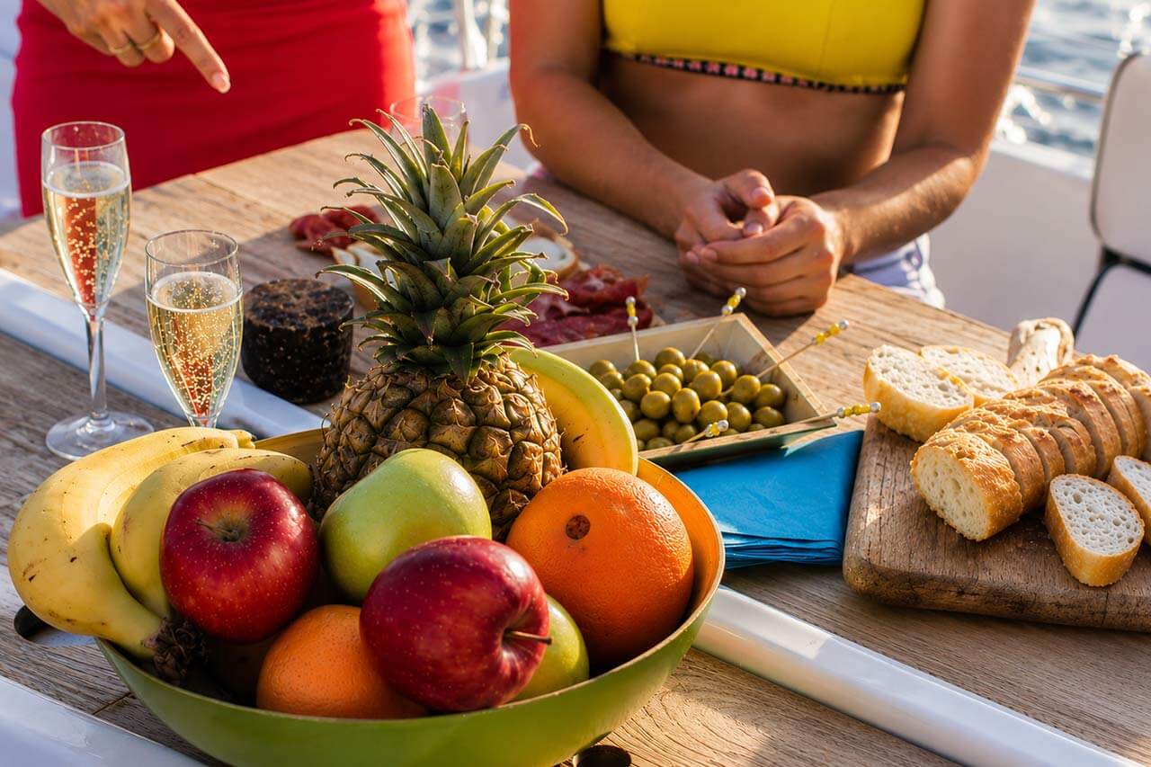 Fruitgajes, brood en drankjes geserveerd aan boord van het zeiljacht Kailani