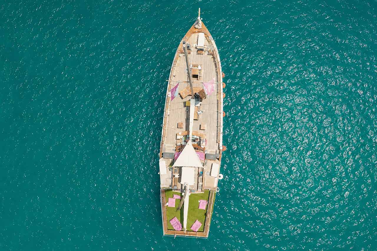 Top-down aerial view of the Utopia party boat surrounded by turquoise Atlantic waters off Tenerife.