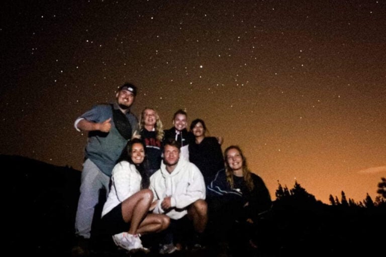 Un gruppo di persone felici che si godono un tour economico di osservazione delle stelle Teide sotto il cielo notturno di Tenerife.