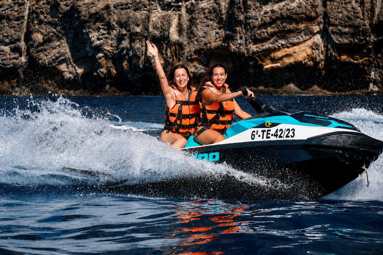 Two women enjoying a Sea-Doo jet ski ride near the Los Gigantes cliffs in Tenerife.