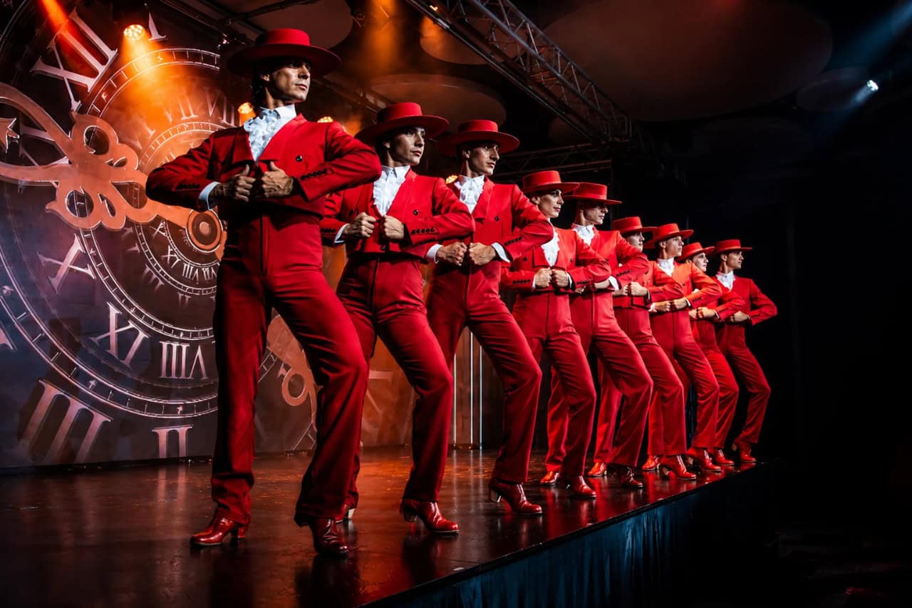 Male dancers in red costumes performing a choreographed routine at the Olé Flamenco Show