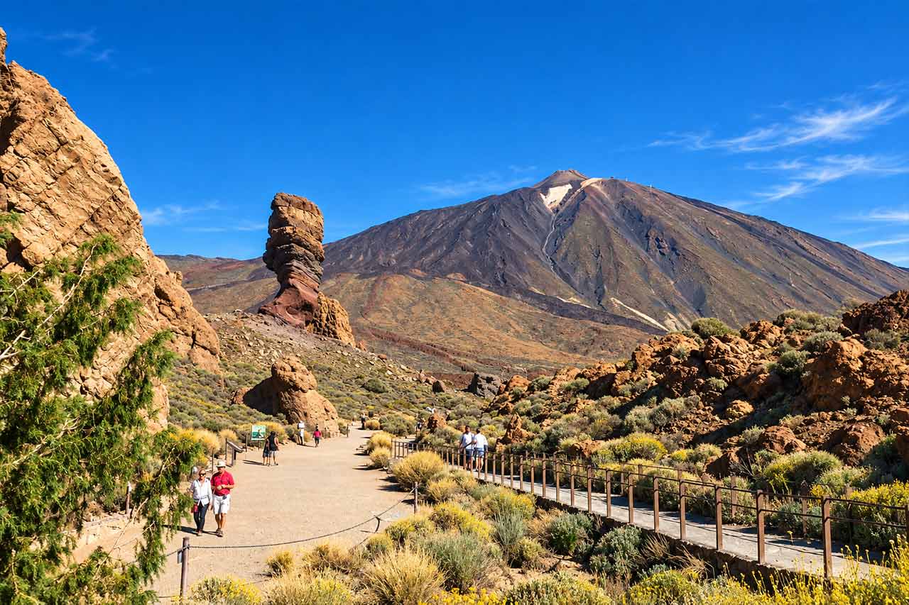 Visitors explore the volcanic landscape around the Roques de García with Mount Teide rising behind them during the first stage of the Teide and Masca bus tour.