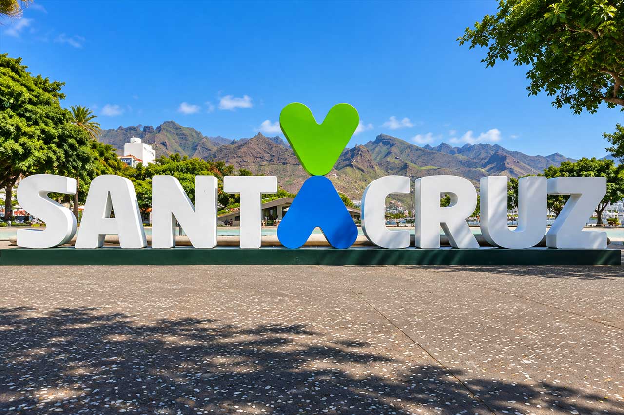 Santa Cruz de Tenerife landmark sign with the Anaga mountains behind it, marking the end of the capital visit before the coach continues to historic La Laguna.
