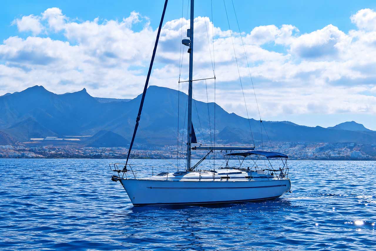 Skyline zeilboot cruisend voor de kust van Tenerife met een prachtige bergachtergrond en kalm Atlantisch water