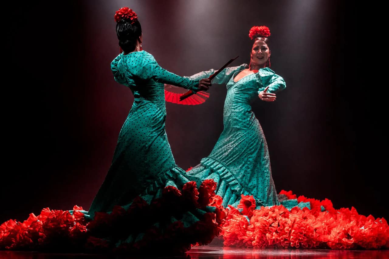Flamenco dancer in traditional dress performing with fan on stage