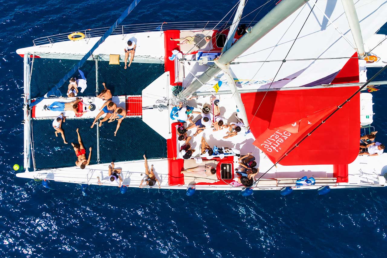 Gasten die zich ontspannen en gezellig met elkaar praten op de ruime dekken en netten van de catamaran White Tenerife