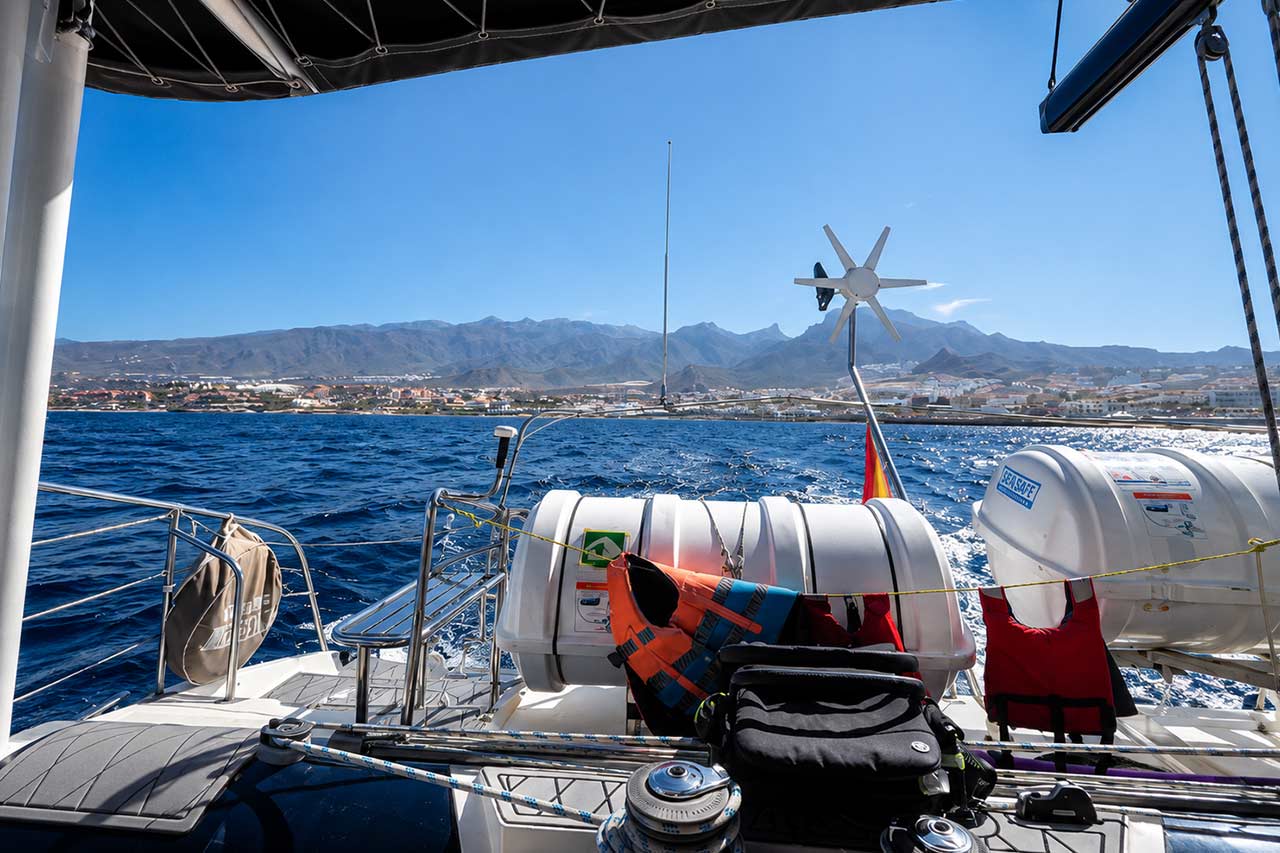 Uitzicht vanaf het schaduwrijke dek van de White Tenerife, met de veiligheidsuitrusting aan boord en de kustlijn van Tenerife in de verte