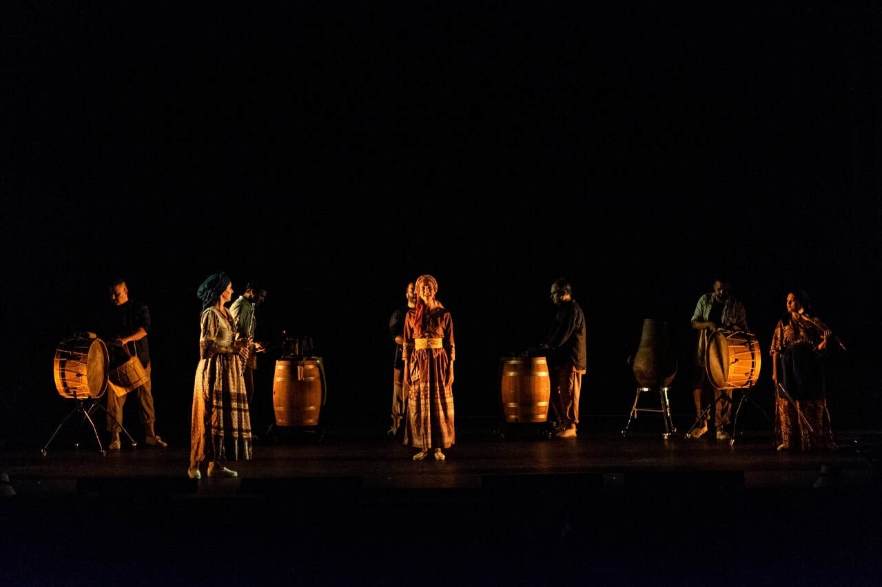 Artiesten met grote trommen en percussie over het verduisterde podium