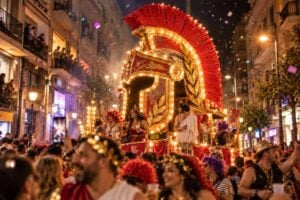 Impresia Cabalgata Anunciadora 2027 din Santa Cruz de Tenerife: un glob de armură romane iluminat pe o stradă îngustă, cu mulțimea care merge alături de el sub confetti, pe timp de noapte