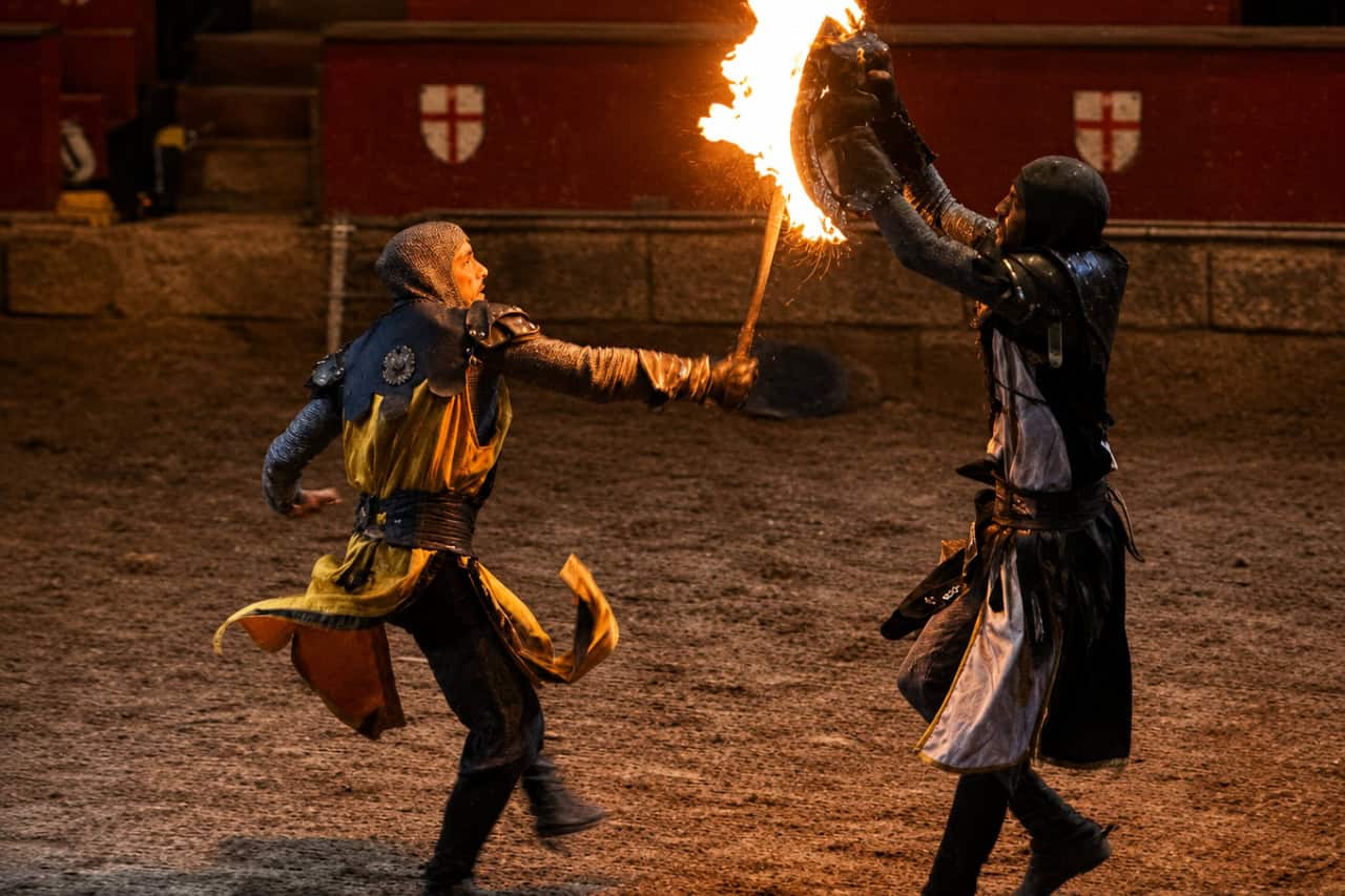 Two armored performers stage a fire combat scene in the arena during a jousting show Tenerife evening.