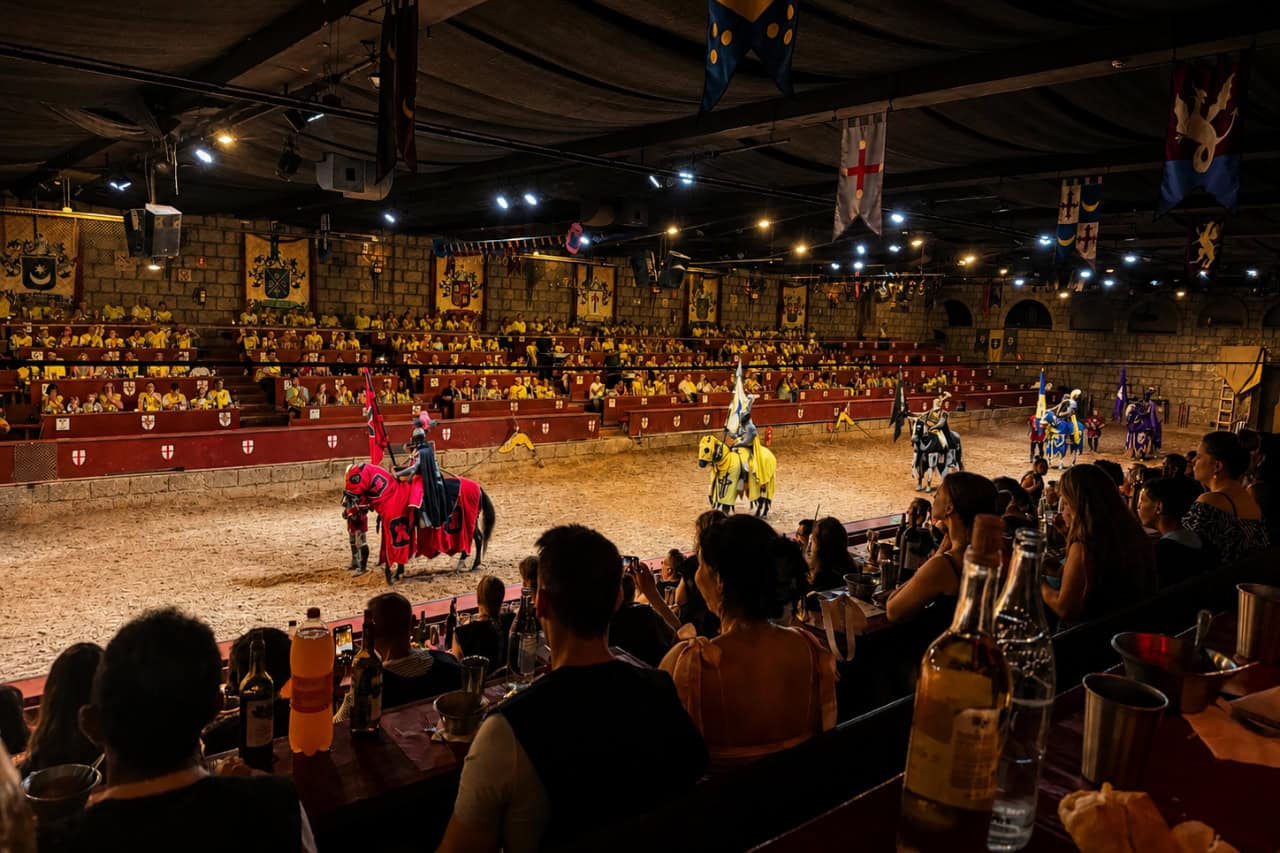 Mounted knights in several team colours perform while guests watch the knights show Tenerife from dining tables.