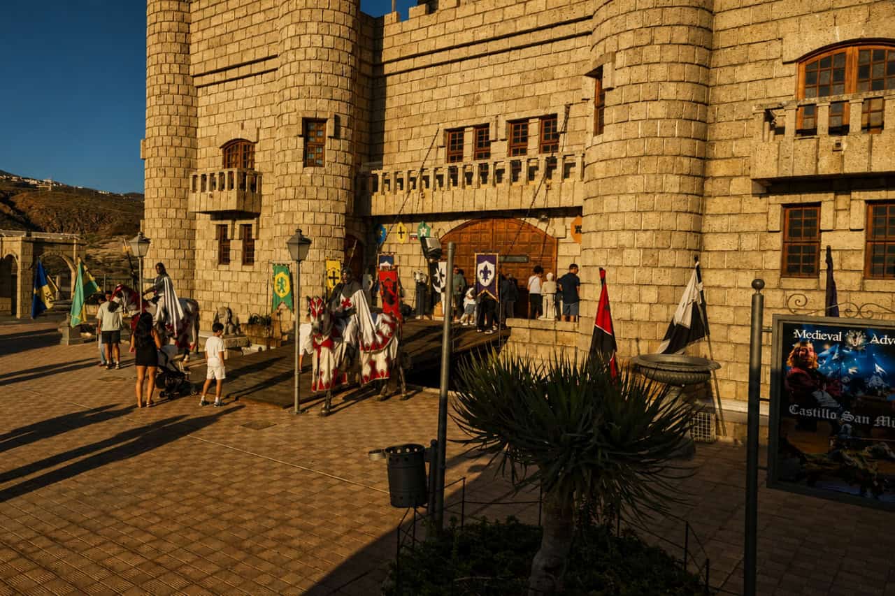 Stone castle entrance with visitors, flags and medieval decorations outside the Medieval Night Tenerife venue.