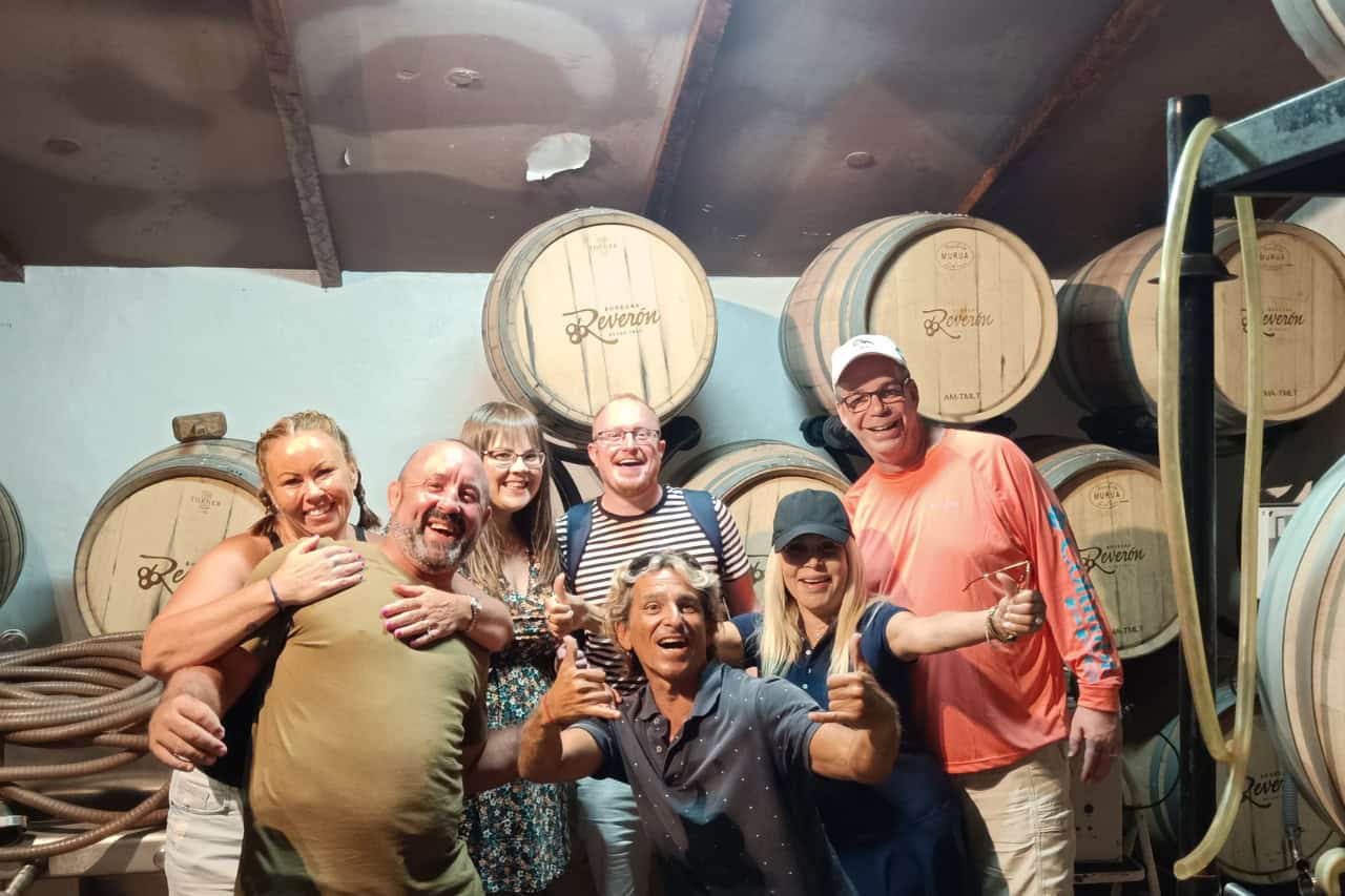 Счастливая группа позирует внутри винодельни на Тенерифе в окружении деревянных бочек с вином во время лучшего винного тура.