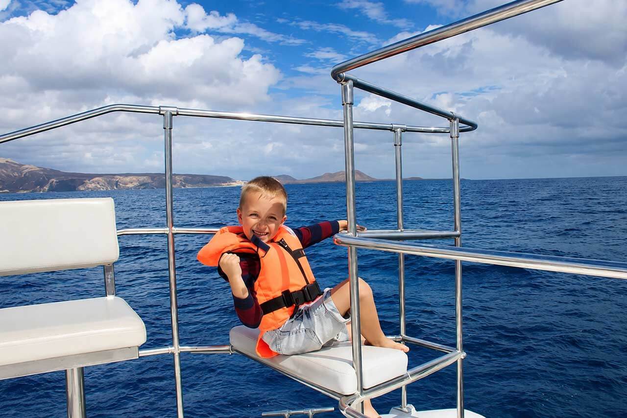 Un jeune passager, vêtu d'un gilet de sauvetage, admire la vue sur la mer à bord du catamaran Monte Cristo à Ténérife.