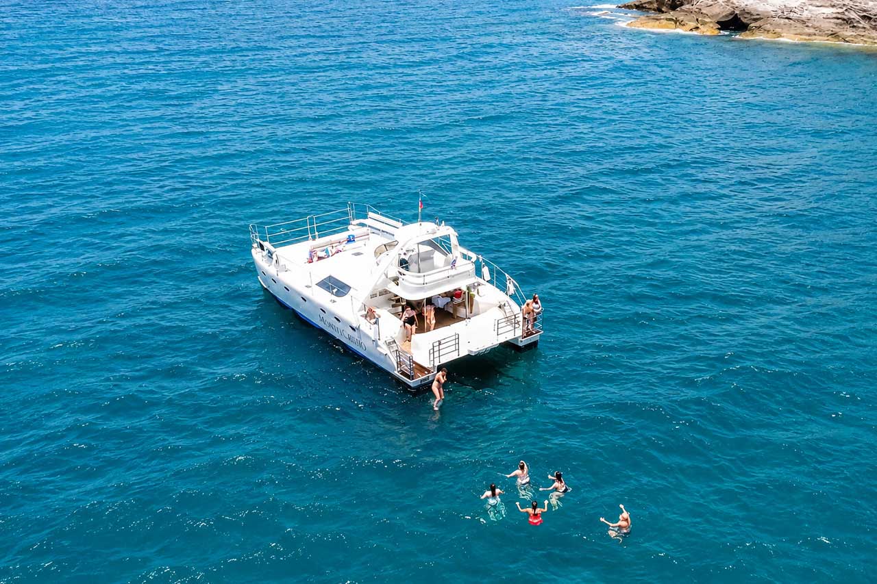 Des vacanciers se baignant dans l'Atlantique à côté du catamaran Monte Cristo lors d'une escale touristique au large des côtes de Ténérife.