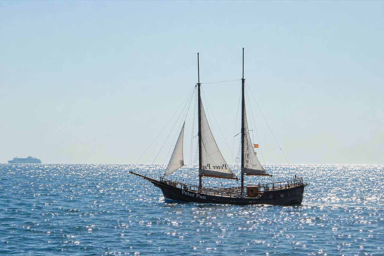 The traditional Peter Pan sailing boat alone on the sparkling Atlantic Ocean near Tenerife, shown as a clean boat-focused scene with no visible guests.