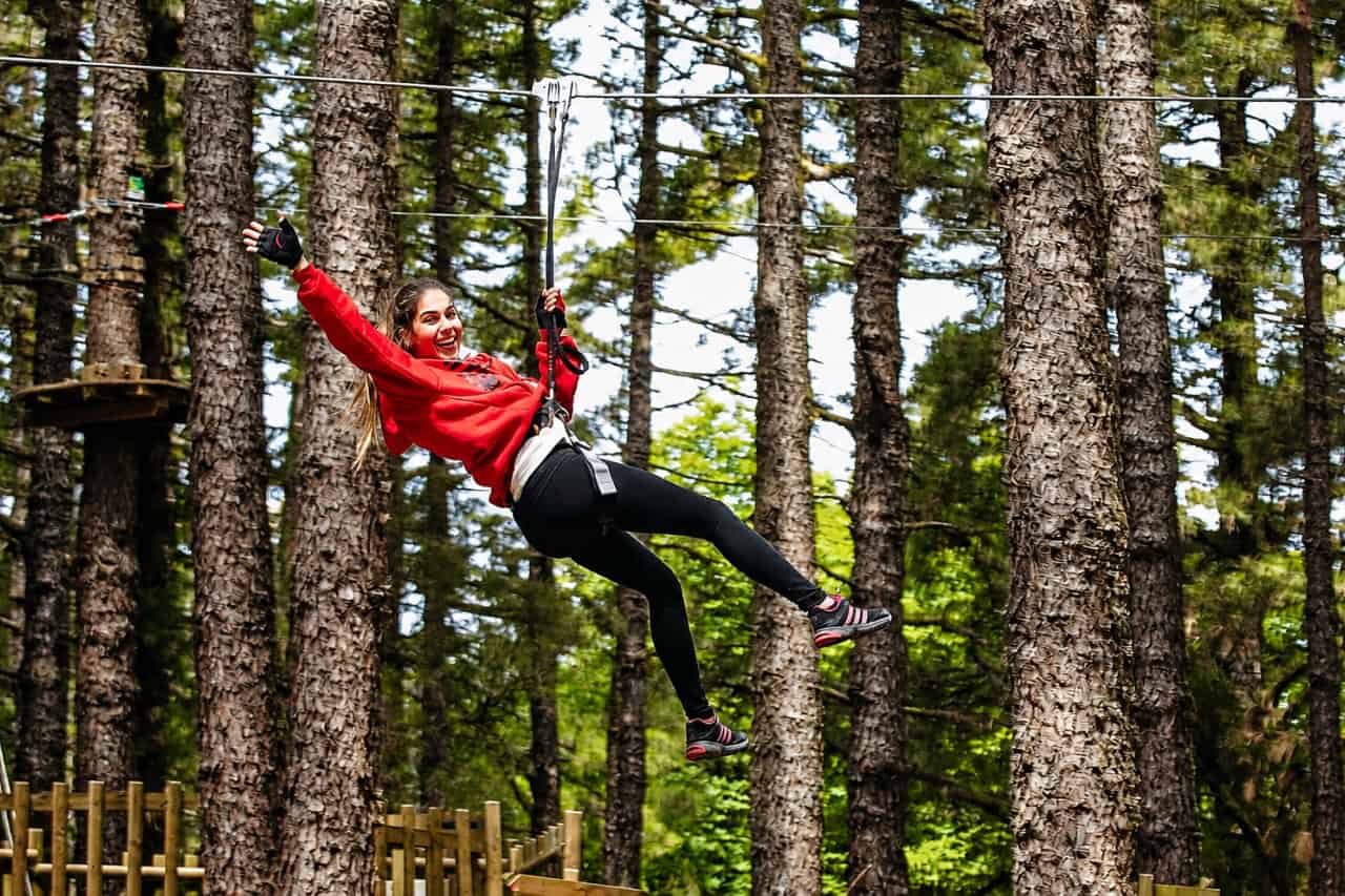 Woman riding a zip line through the pine forest at Forestal Park Tenerife