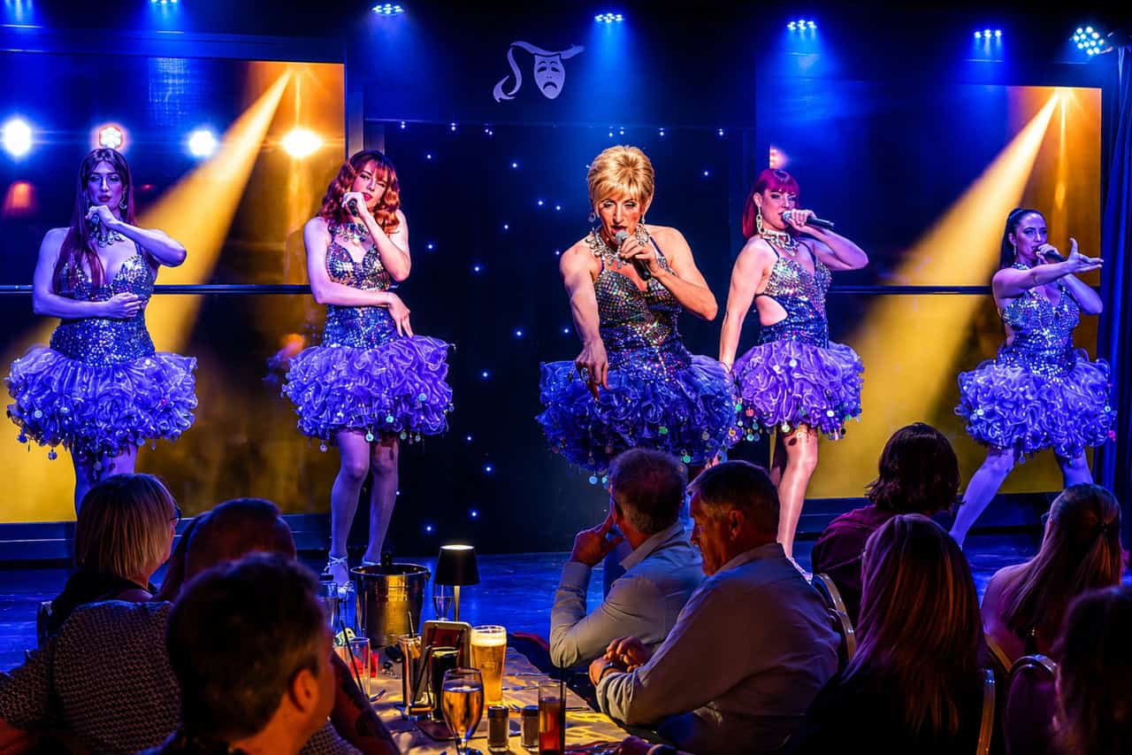 A drag performer pointing at a guest while singing on stage