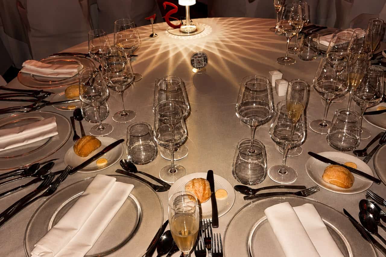 Round dinner table set with plates, folded napkins and glassware for a dinner show Tenerife experience.
