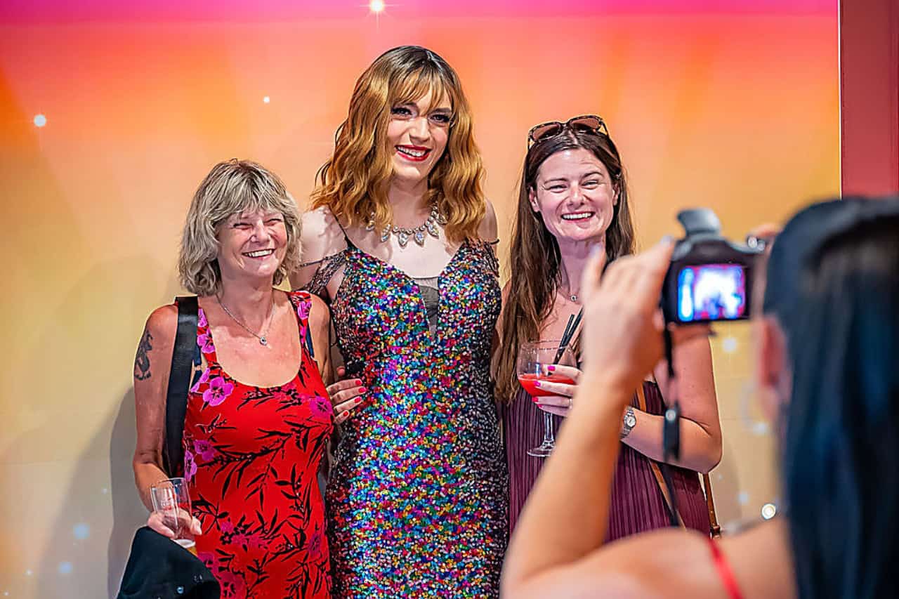 Two guests posing with a drag performer for the free souvenir photo