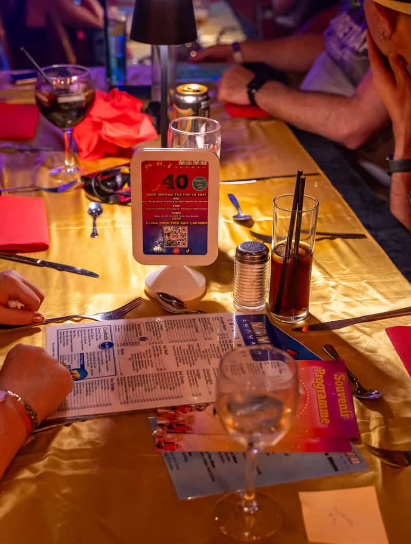MHT drag dinner show Tenerife table setup with drinks menu and souvenir programme Playa de las Americas