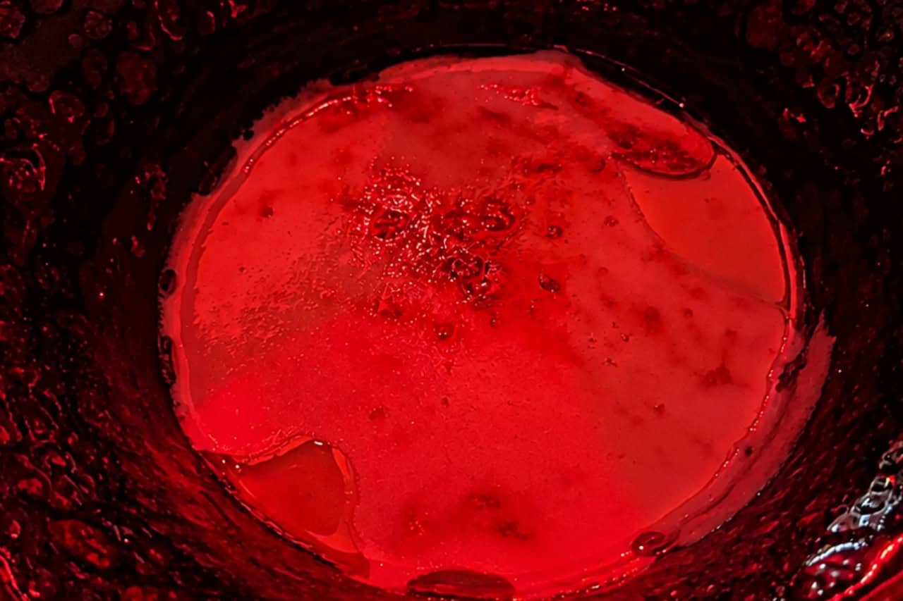 Example of a plated course soup in a black bowl under red lighting at the Scandal Dinner Show Tenerife.