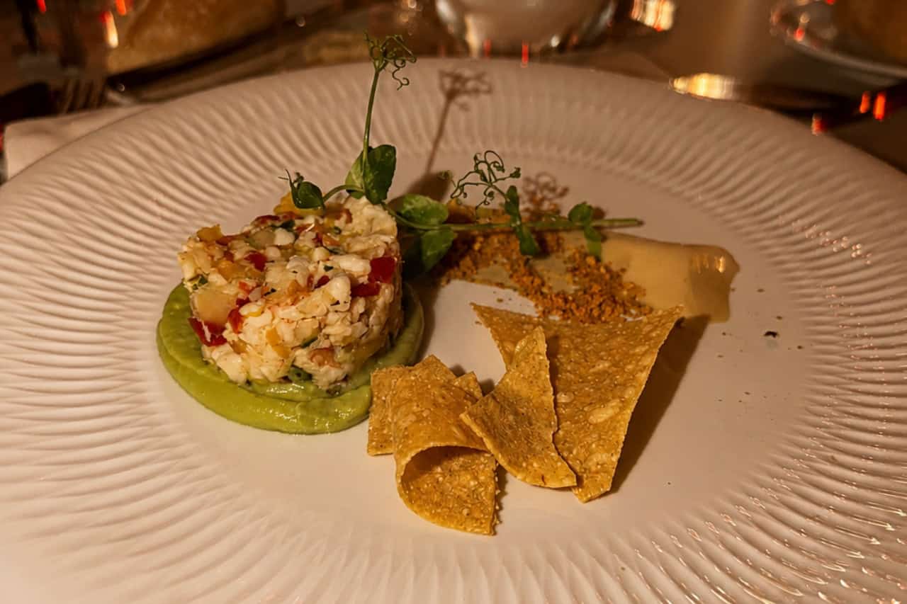 Example of a plated course with diced ingredients, green puree, crisp pieces and garnish at the Scandal tasting menu.