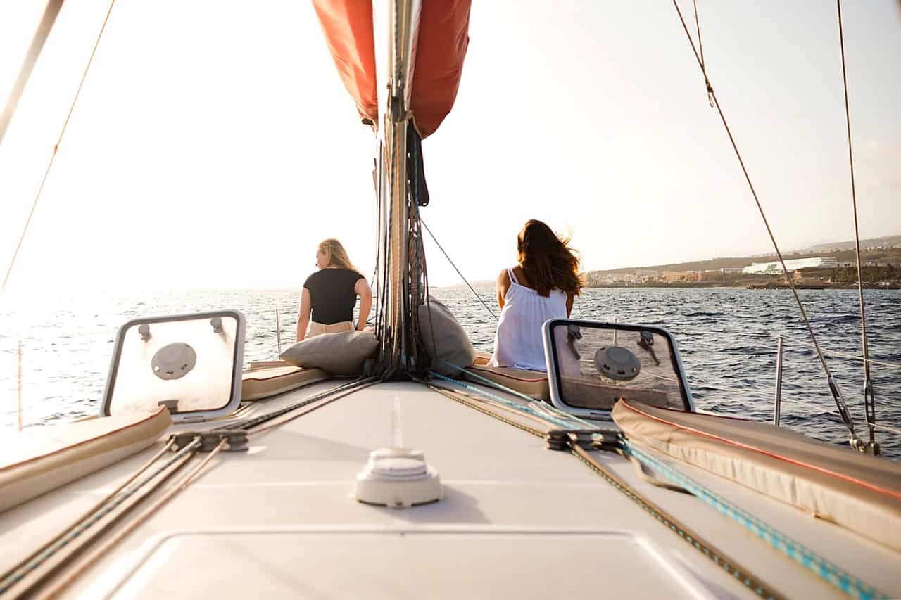 Guests relax on the bow of the Atlantic Star sailing boat as it leaves Puerto Colón for a small-group whale-watching tour in Tenerife.