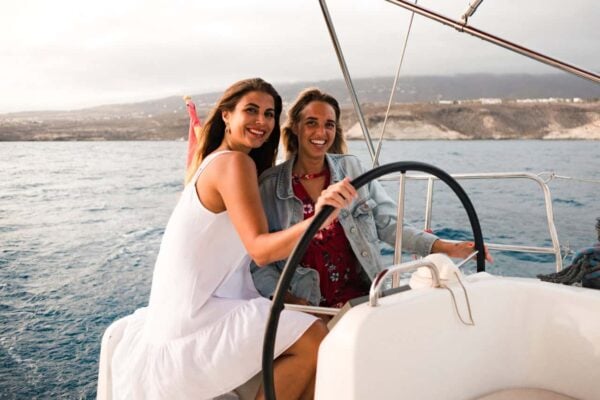 Smiling women enjoying steering the Atlantic Star yacht on a whale watching excursion in Tenerife