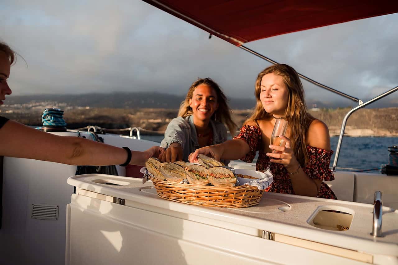Guests share sandwiches and drinks on board the Atlantic Star during a relaxing small-group whale-watching trip in Tenerife.