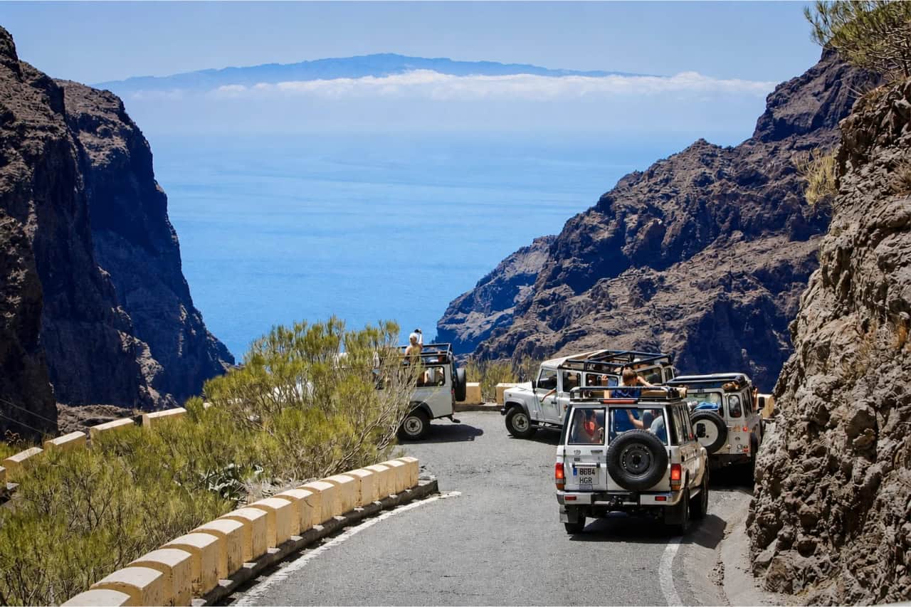 Safari jeeps driving along a winding mountain road with spectacular panoramic views