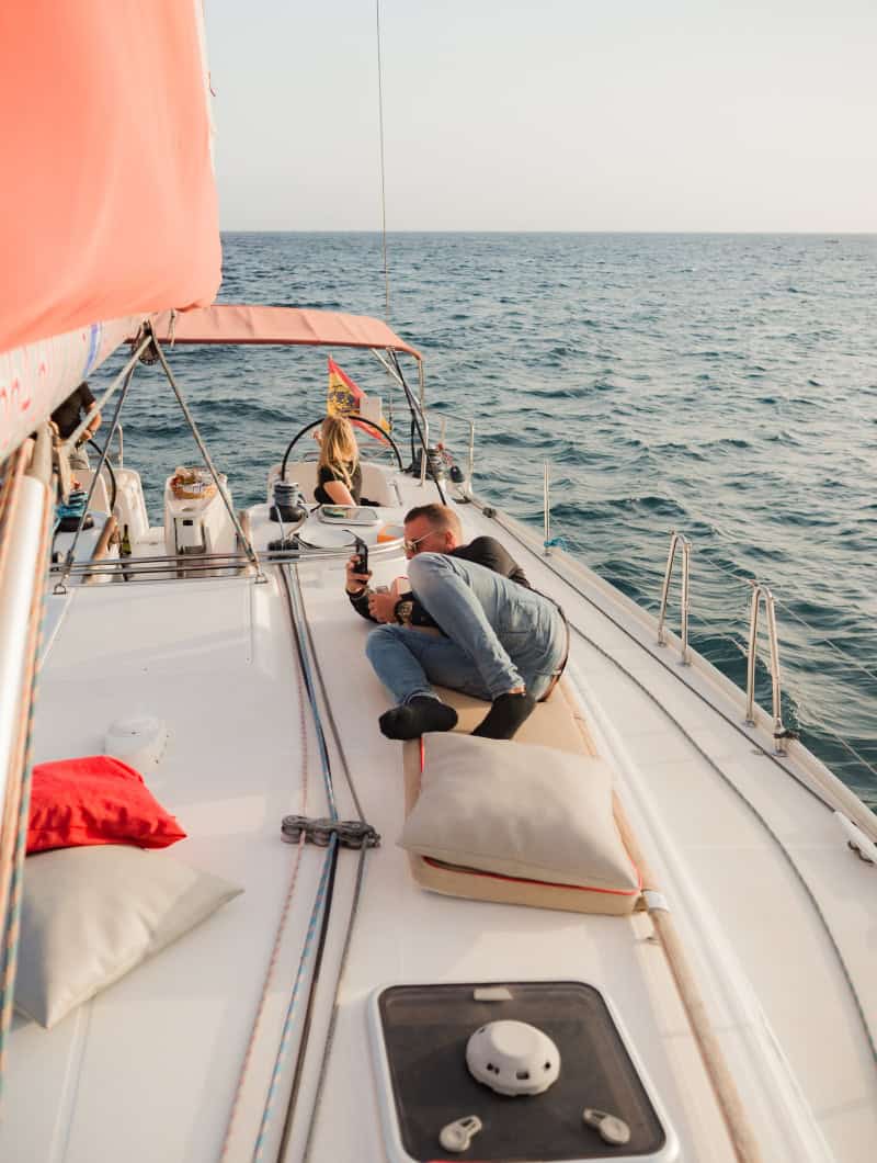 Guest lying on the deck of a private boat trip in Tenerife taking photos, with the whole sailing yacht to themselves