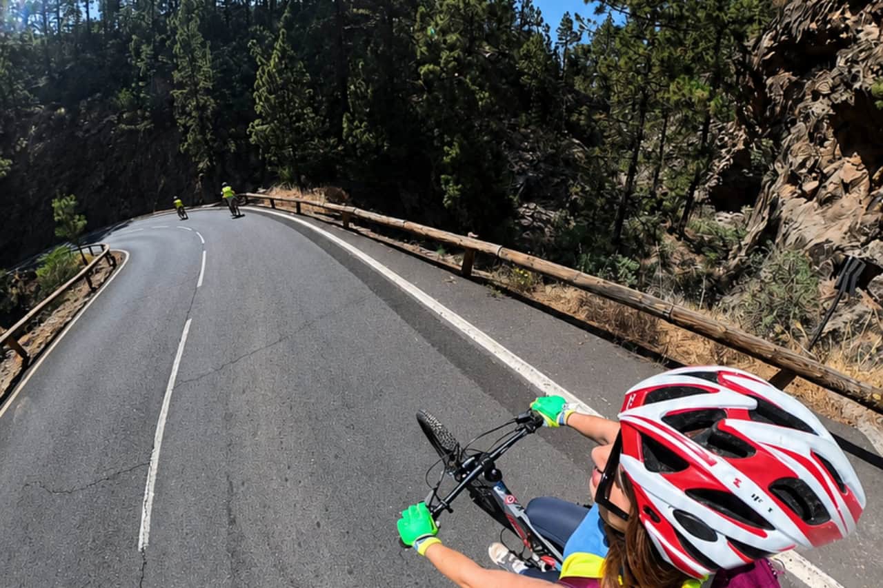 Cyclists following the guide on a paved mountain road through Tenerife's pine forest