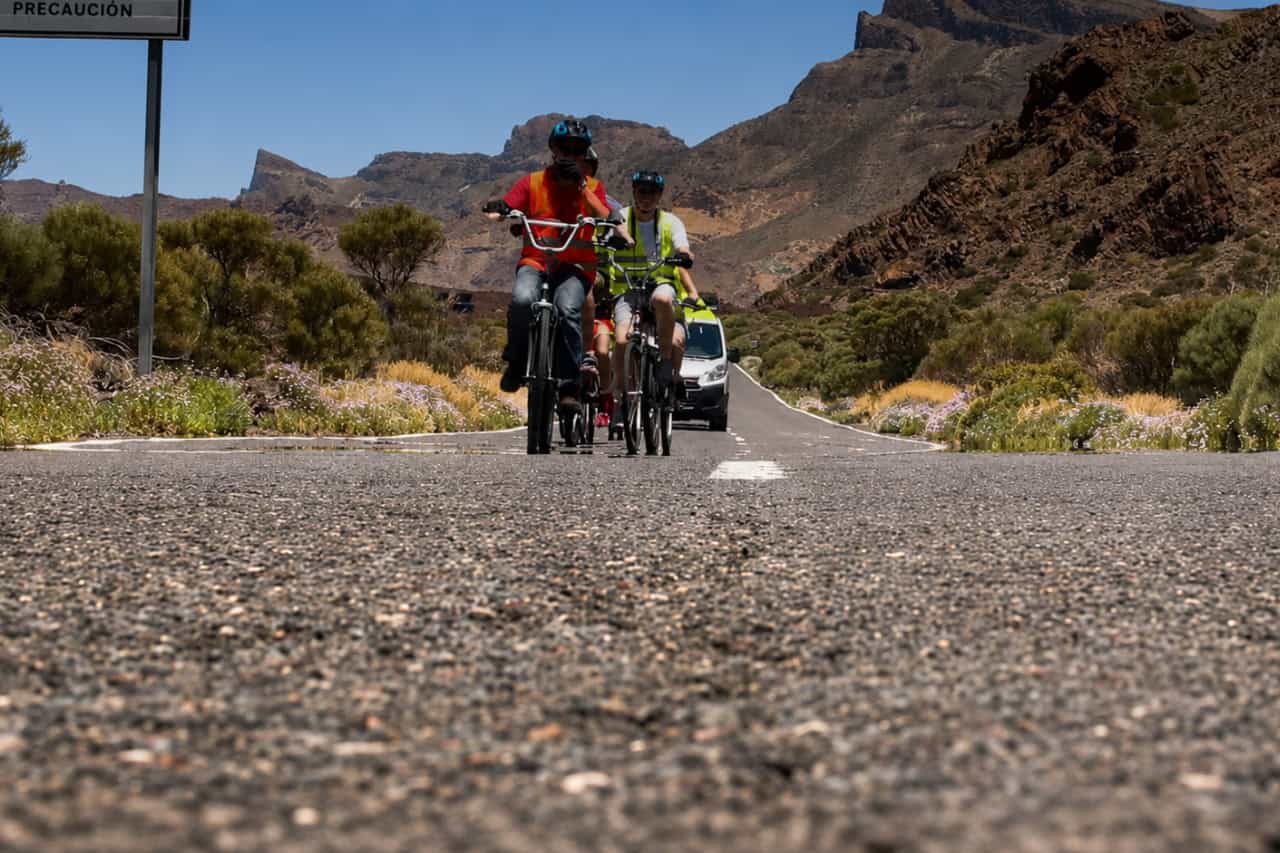 Cyclists riding through Mount Teide's volcanic landscape with a support vehicle following