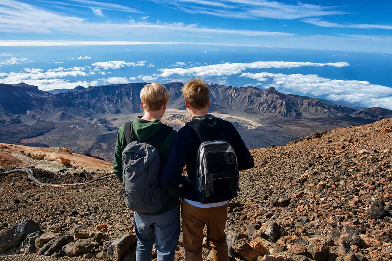 Two hikers overlooking the Teide caldera and volcanic landscape during the Official Teide Hike in Tenerife.