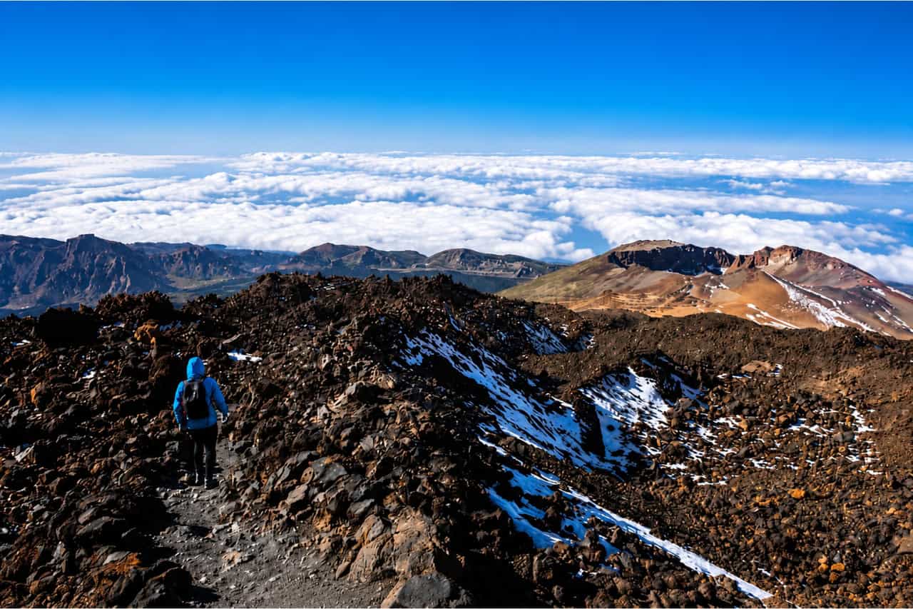Hiker walking along a volcanic mountain trail during the Official Teide Hike in Tenerife.