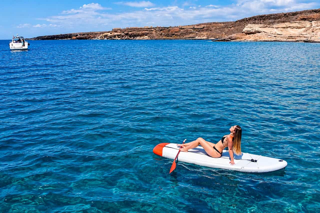 Guest paddleboarding beside the Bellini yacht
