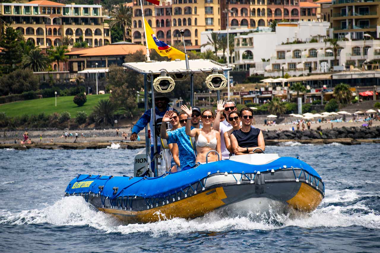Külalised nautimas kiiret Sea Safari kiirpaadisõitu Tenerifel, sõites mööda rannikut sinisel RIB-paadil Atlandi ookeani ekskursiooni ajal