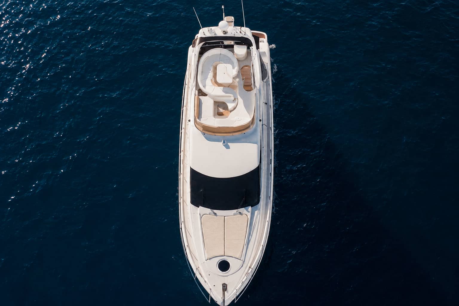 A top-down drone view of the white Seaduction motor yacht surrounded by the dark blue Atlantic Ocean, showing the spacious bow, shaded central deck and curved upper-deck seating area.