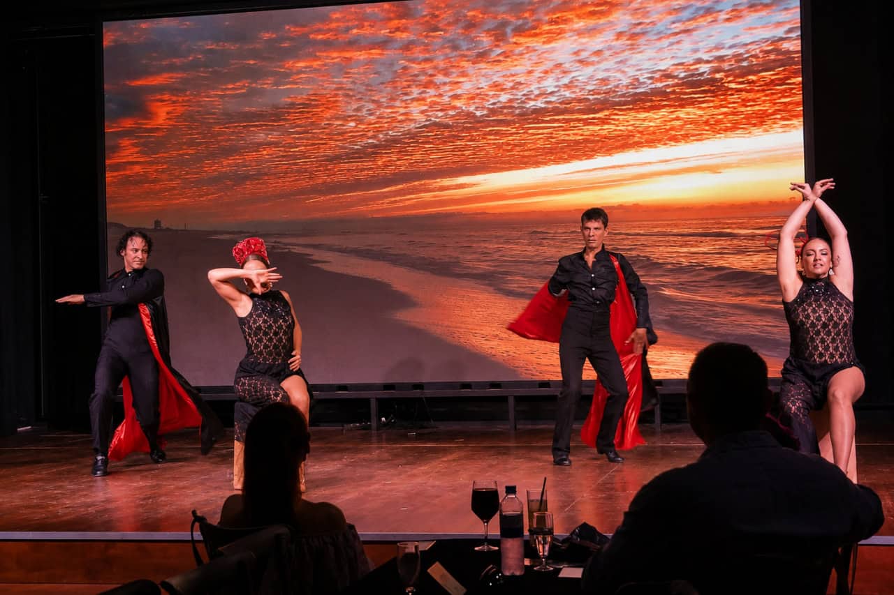 Four dancers in black and red costumes perform on stage during a Flamenco show Tenerife performance.