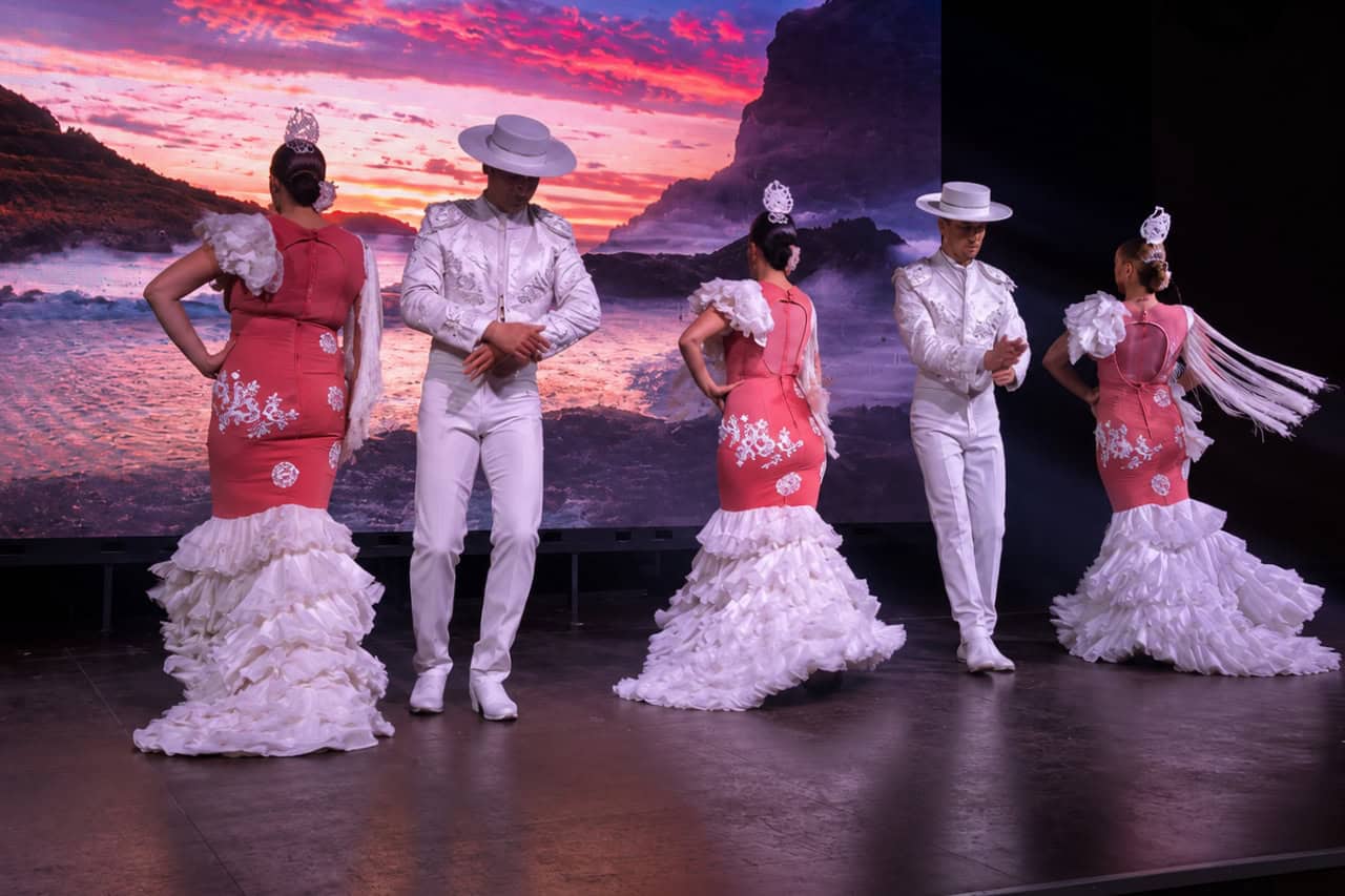 Dancers in red and white costumes perform on stage during Friday night flamenco Tenerife.