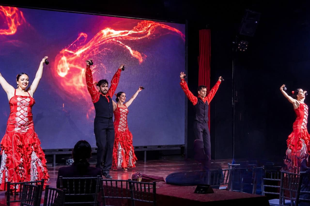 Five dancers in red costumes perform on stage during the Spanish dance show Tenerife.