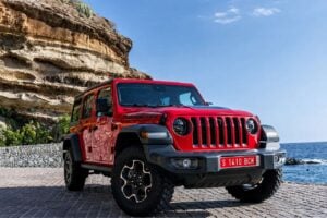 Red Jeep Wrangler for rent in Tenerife with a scenic ocean and cliff backdrop.