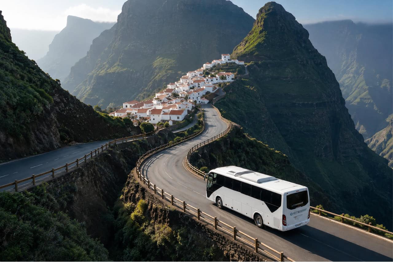 Tour bus travelling through the spectacular Masca Valley in Tenerife, passing dramatic mountain roads, traditional Canarian houses and breathtaking volcanic landscapes.