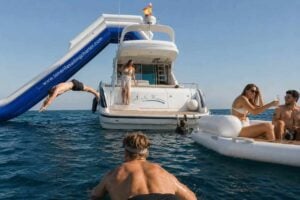 Guests enjoying a luxury day at sea aboard the No Worries Yacht in Tenerife, relaxing on floating loungers, swimming in crystal-clear waters, and using the yacht’s inflatable slide during a private yacht charter experience.