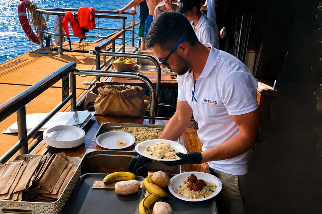 Freebird crew serving food on board during a group charter, showing the catering experience available for corporate outings, incentive trips and private events in Tenerife.