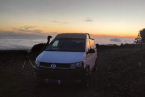 Белый фургон с телескопом, установленный на Mount Teide во время заката над облаками, готов к звездному туру.