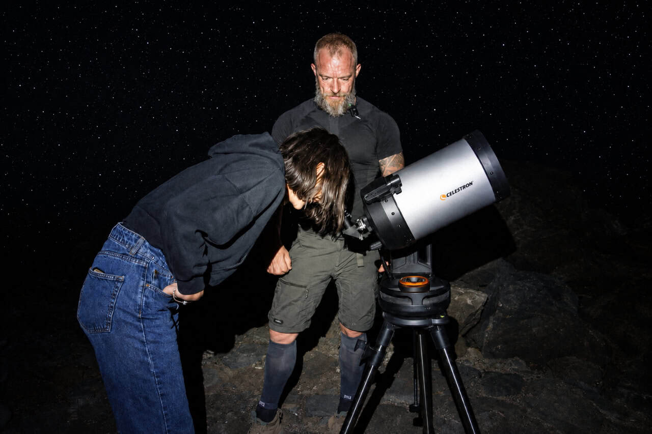 Huésped observando el cielo nocturno a través de un telescopio en el Teide