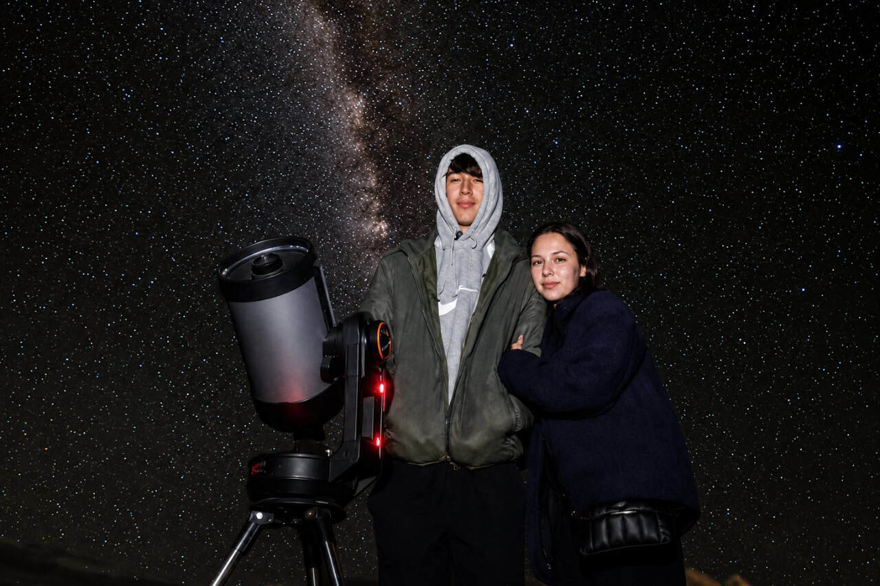 Pareja junto a un telescopio durante una excursión nocturna de observación de estrellas en el Teide